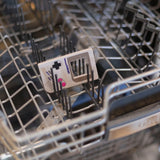 A Bumkins Silicone Teether: Game Boy™ is on the top rack of an open dishwasher.