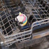 Bumkins Silicone Teether: Unicorn sits on the upper rack of an open dishwasher. The metal prongs cradle it amid the shining compartments, resembling teethers ready to soothe tiny gums.