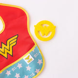 Red and yellow bib with a W logo and a yellow silicone teether shaped like Wonder Womans winged W, by Bumkins.