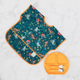 A Bumkins Junior Bib: Jungle with animal patterns pairs perfectly with a matching orange plate on a marble surface.