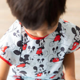 Child in a Bumkins Mickey Mouse Classic short-sleeved smock looks down.