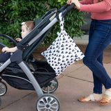 A woman pushes a stroller with a baby, carrying the Bumkins Wet Bag: Hearts, made from waterproof fabric.