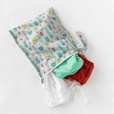 A Wet Bag: Cacti by Bumkins, holds a red cloth diaper, white cloths, and a small bottle on waterproof fabric.