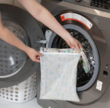 Someone places a Bumkins Wet Bag: Cacti with heat-sealed seams into a front-loading washing machine.