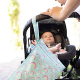 A baby is in a stroller with a Bumkins Wet Bag: Rainbows hanging from the handle, being pushed by someone.