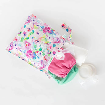 Bumkins Wet Bag: Watercolor includes pink/green cloth diapers, a bottle, and a white cloth on waterproof fabric.