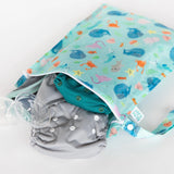 A colorful Wet Bag: Ocean Life by Bumkins, featuring a teal cloth diaper and a clear bottle part peeking out. Perfect for reusable needs.