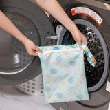 A Bumkins Wet Bag: Ocean Life is placed in a front-loading washer, flaunting its colorful, reusable charm.