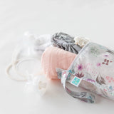 Floral Wet Bag by Bumkins, pink muslin cloth, gray waterproof fabric, and clear tubing displayed on a white surface.