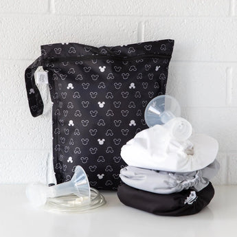 The Bumkins Wet Bag: Mickey Mouse Icon Black + White, features waterproof design alongside three folded cloth diapers and breast pump parts.