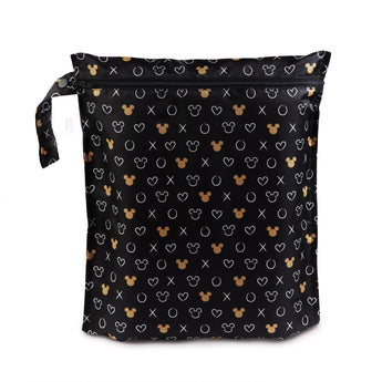 The Bumkins Wet Bag: Minnie Mouse Icon Black + White is a black zippered pouch made of waterproof fabric, featuring golden Mickey silhouettes and white criss-cross designs. Ideal for wet items, it includes a handle on the zipper for easy carrying.