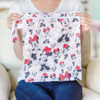 A person holds the Bumkins Wet Bag: Minnie Mouse Classic, featuring a cartoon mouse in red bows on waterproof fabric.