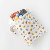 The Bumkins Wet Bag: Winnie and Friends, filled with toiletries, a small towel, and a brown pouch, rests on a white background.