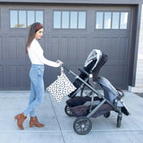 Woman wears jeans, white top, and brown ankle boots while pushing a double stroller with Bumkins Wet/Dry Bag: Hearts in front of a garage.