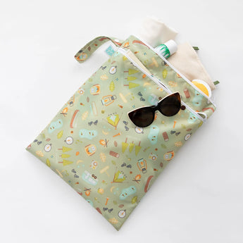 Bumkins Wet/Dry Bag: Camp Gear has a green camping-themed design and includes a beige towel, sunglasses, and sunscreen. Waterproof too!.