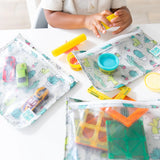 A child plays with toys and playdough at a table. Nearby are TSA-compliant Bumkins Clear Travel Bag 3-Pack: Cacti filled with toy cars.