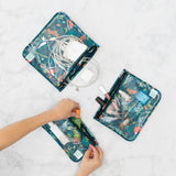 The Bumkins Clear Travel Bag 3-Pack: Jungle holds cables, electronics, and makeup on a white marble surface. TSA-compliant and colorful!.