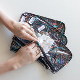 Hands organizing the Bumkins Clear Travel Bag 3-Pack: Channel Kindness on a white surface.