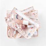 Three Bumkins Princess Magic clear travel bags, TSA compliant with pink floral patterns, are stacked on a white surface.