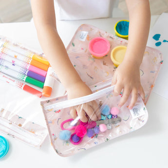 A child organizes markers in Bumkins Clear Travel Bag 3 Pack: Princess Magic on a white table.