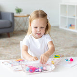 Young girl crafting happily, surrounded by Bumkins lightweight, waterproof Clear Travel Bag 3 Pack: Princess Magic.