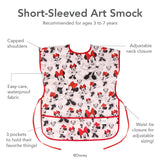 Discover Bumkins Short-Sleeved Smock: Minnie Mouse Classic, perfect for ages 3 to 7 with an adjustable fit, capped shoulders, neck closure, and waist tie. Made from easy-care waterproof fabric featuring three front pockets and Disneys beloved character.