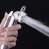 A hand holds a Bumkins Cloth Diaper Sprayer, spraying water with adjustable pressure against a black background.